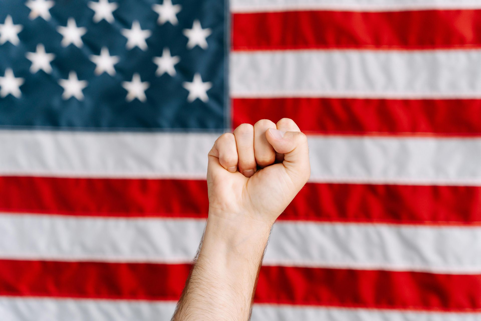 A raised fist in front of an American flag, symbolizing patriotism and activism.