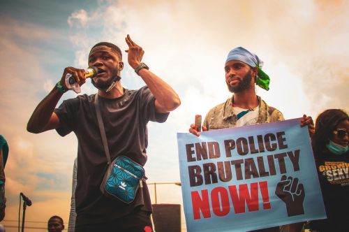 Protesters hold signs and speak during an outdoor rally against police brutality in Nigeria.